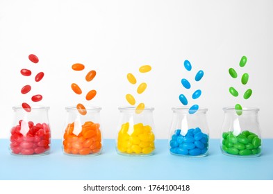 Delicious color jelly beans falling into jars on light blue table - Powered by Shutterstock