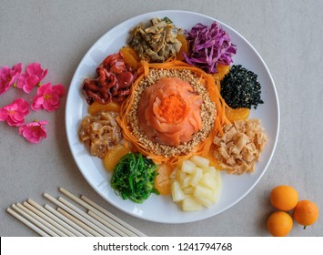 Delicious and colorful display of Chinese prosperity cuisine / Yee Sang aka Prosperity Toss / Carrot strips, purple cabbage, fresh seaweeds, jelly fish, deep fried fish skin, ground peanuts, fritters