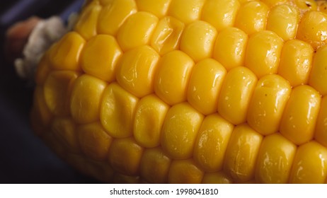 Delicious Corn On The Cob Captured In An Extreme Close Up. The Brightly Glowing Yellow Kernels Form A Recognizable Pattern. The Cob Was Buttered Up, And Fried In An Iron Cast Skillet. 