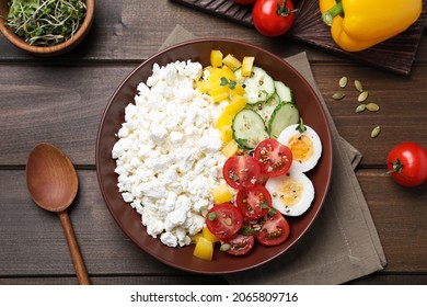 Delicious cottage cheese with vegetables and boiled egg served for breakfast on wooden table, flat lay