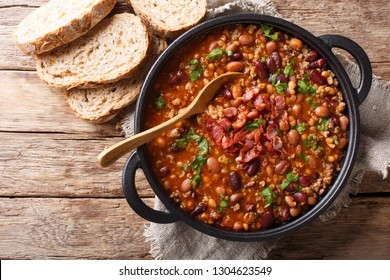 Delicious cowboy stew of beans with ground beef, bacon in a spicy sauce closeup in a bowl on the table. Horizontal top view from above
