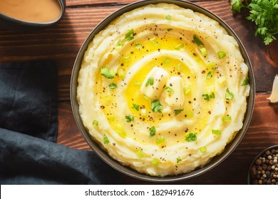 Delicious creamy mashed potatoes with butter, fresh herbs and freshly-cracked black pepper. Top view with close up.