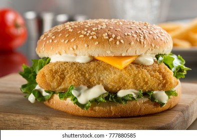 A Delicious Crispy Fish Burger With Cheese, Lettuce, And Mayonnaise.