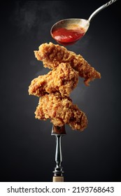 Delicious crispy fried chicken with tomato sauce. Fried chicken with ketchup on a fork.