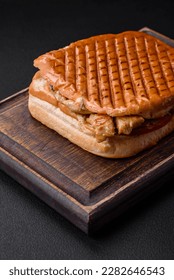 Delicious crispy sandwich with chicken breast, tomatoes, ketchup and spices on a dark concrete background - Shutterstock ID 2282646543