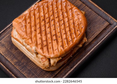 Delicious crispy sandwich with chicken breast, tomatoes, ketchup and spices on a dark concrete background - Shutterstock ID 2282646545
