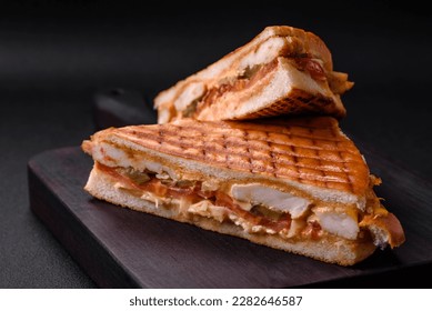Delicious crispy sandwich with chicken breast, tomatoes, ketchup and spices on a dark concrete background - Shutterstock ID 2282646587