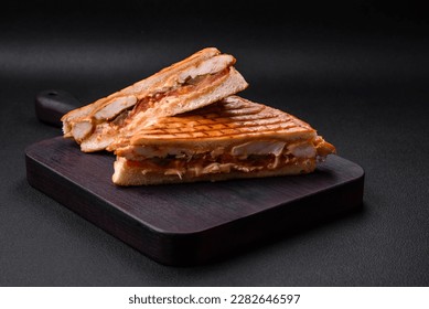 Delicious crispy sandwich with chicken breast, tomatoes, ketchup and spices on a dark concrete background - Shutterstock ID 2282646597