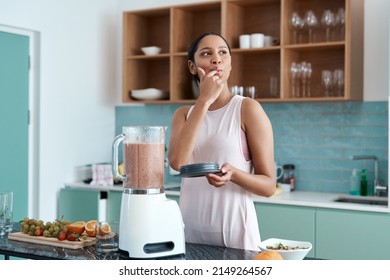 Delicious. Cropped shot of an attractive young woman making smoothies in her kitchen at home. - Powered by Shutterstock