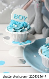 Delicious Cupcake With Light Blue Cream And Boy Topper For Baby Shower On White Wooden Table