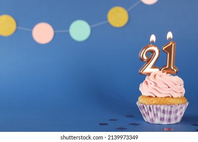 Delicious Cupcake With Number Shaped Candles On Blue Background, Space For Text. Coming Of Age Party - 21th Birthday
