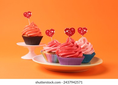 Delicious cupcakes with bright cream and heart toppers on orange background - Powered by Shutterstock