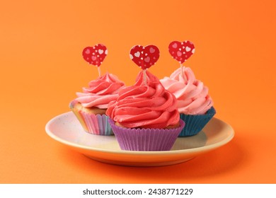 Delicious cupcakes with bright cream and heart toppers on orange background - Powered by Shutterstock