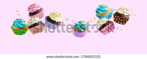 Delicious Cupcakes\
for party, birthday. Various cupcakes with pink white and blue\
cream flying over pink\
background