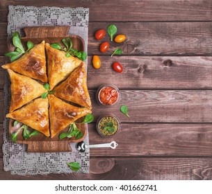 Delicious Deep Fried South Indian Samosa Pies With Meat, Lettuce, Mint Chutney And Tomato Sauce On A Wooden Background In Rustic Style, Empty Place For Text, Top View