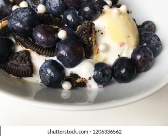 Delicious Dessert, Ice-cream With Crushed Oreo Cookies, Blueberries And Sugar Pearls In A White Bowl, Close-up View