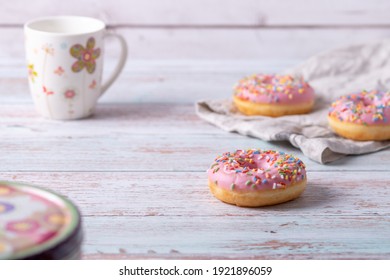 Delicious donuts with pink icing and colorful sprinkles on wooden background. Sweet pastry for a coffee klatch, as a snack for birthday party or other celebrations. Pastel colors, light and airy. - Powered by Shutterstock