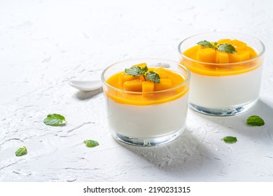 Delicious double colored mango panna cotta mousse pudding with diced mango pulp flesh topping on white table background.