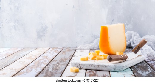 Delizioso formaggio gouda olandese con cubetti di formaggio e coltello speciale su vecchio tavolo di legno. Copia spazio.