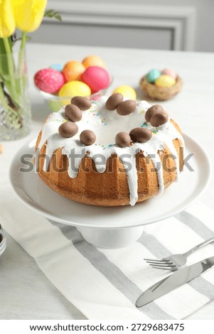 Delicious Easter cake, painted eggs and yellow tulips on white table indoors, closeup