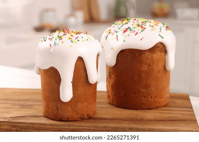 Delicious Easter cakes with sprinkles on wooden board in kitchen, closeup