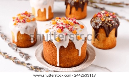 Delicious Easter Kulich cakes, festively decorated with glaze and colorful toppings, accompanied by willow branches signaling the arrival of spring