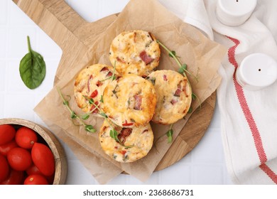 Delicious egg muffins with cheese and bacon on white tiled table, flat lay - Shutterstock ID 2368686731