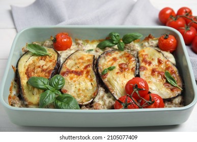 Delicious eggplant lasagna in baking dish on white wooden table