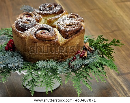 A delicious and festive Cinnamon Roll Coffeecake decorated with red cherries and powdered sugar sits on a cake stand with spruce branches, cedar, cinnamon sticks and red currants on a wooden table Stock foto © 