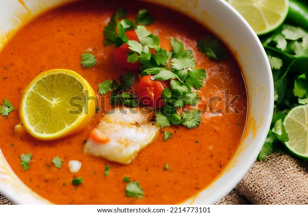 Delicious fish soup with\
tomato, lime, red pepper, coconut milk and cilantro. Photo realism\
illustration