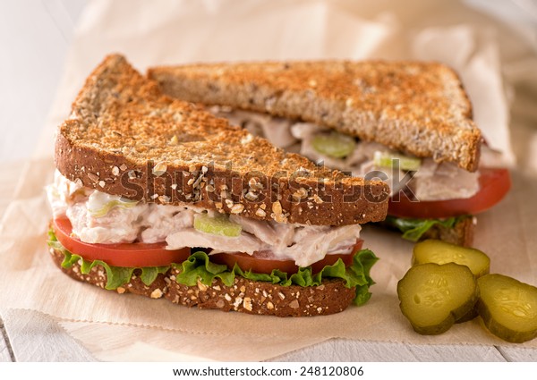 A delicious flaked white tuna\
salad sandwich with tomato, lettuce, mayonnaise, and\
pickles.