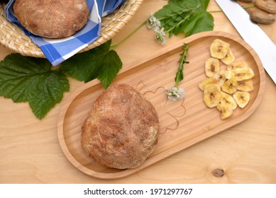 Delicious, Fluffy Ciabatta, Italian Flat Bread; Sandwich Bread And Dry Banana Slices On Wooden Board With Delicious Pita Breads In Breadbasket And Peanuts In Background
