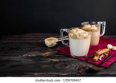 Delicious and fragrant dalgona coffee in glass cups, cinnamon sticks, dried mushrooms, a spoon of instant coffee, sugar. Cooling coffee drink with milk