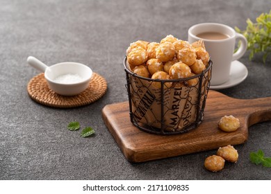 Delicious French Chouquette Choux Pastry dessert Pearl Sugar Puff in a basket on gray table background, afternoon tea concept.