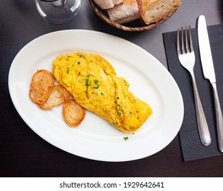 Delicious french omelet with cheese and fresh herbs served with toasts on white plate - Shutterstock ID 1929642641