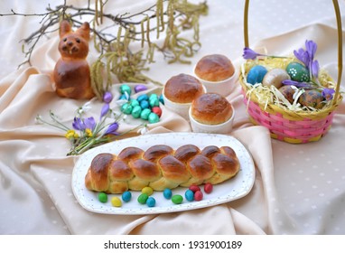 Delicious fresh baked Easter breads: braided bread, small sweet bread buns - Easter cakes in baking molds and brioche bun in a shape of Easter bunny with Easter eggs and spring flowers in background