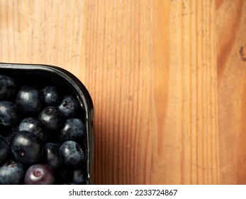 Delicious fresh blueberries in a black container on a wooden table background. close-up. selective focus. free text space. copy space - Shutterstock ID 2233724867