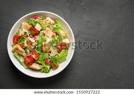 Delicious fresh Caesar salad on black table, top view. Space for text