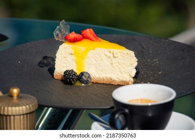 Delicious fresh cheesecake with berries and a cup of coffee on a table in a street restaurant - Powered by Shutterstock