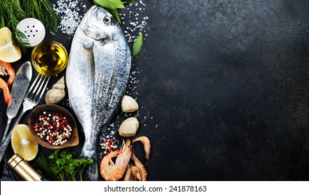 Delicious fresh fish on dark vintage background. Fish with aromatic herbs, spices and vegetables - healthy food, diet or cooking concept  - Shutterstock ID 241878163