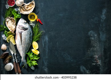 Delicious Fresh Fish And Oysters With Aromatic Herbs, Spices And Vegetables On Dark Slate Plate