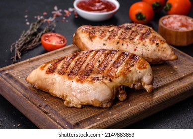 Delicious fresh grilled chicken fillet with spices and herbs on a dark concrete background. A dish cooked over fire