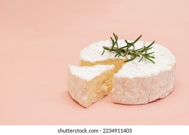 Delicious fresh italian Camembert cheese. Fresh Camembert cheese with rosemary on pink background. Top cheese of Italy - Camembert. Italian camembert cheese side view.