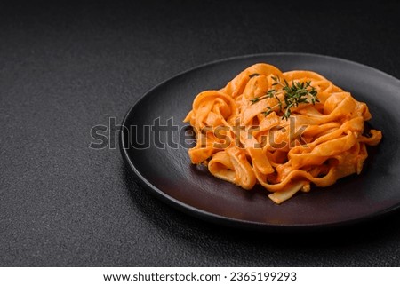  Delicious fresh pasta with pesto sauce, salt, spices and herbs on a ceramic plate on a textured concrete background
