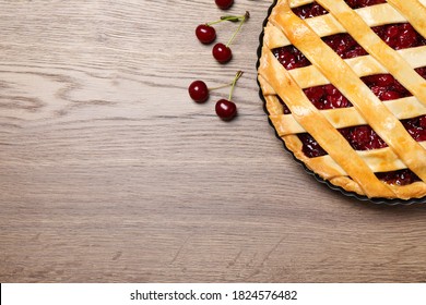 Delicious fresh pie and cherries on wooden table, flat lay. Space for text