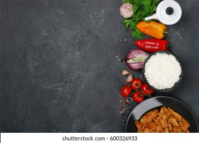 Delicious and fresh roasted slices of curry chicken with rice and vegetables on a dark concrete background, top view, right frame layout with free text copy space horizontal - Powered by Shutterstock