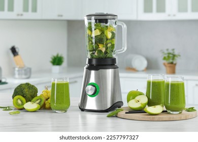 Delicious fresh smoothie and blender with ingredients on white marble table in kitchen