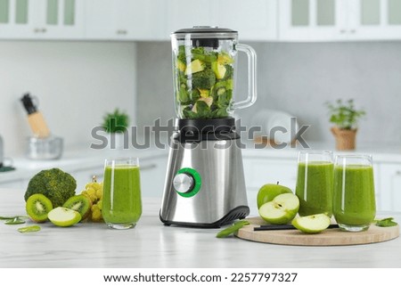Delicious fresh smoothie and blender with ingredients on white marble table in kitchen