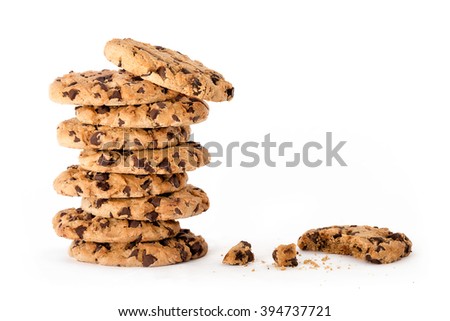 Delicious freshly baked chocolate chip cookies in a tall stack, next to a partially eaten one with crumbs isolated on white background with copy space for text