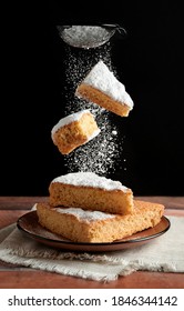 Delicious freshly baked sponge cake whit two piece of cake falling and sprinkling icing sugar